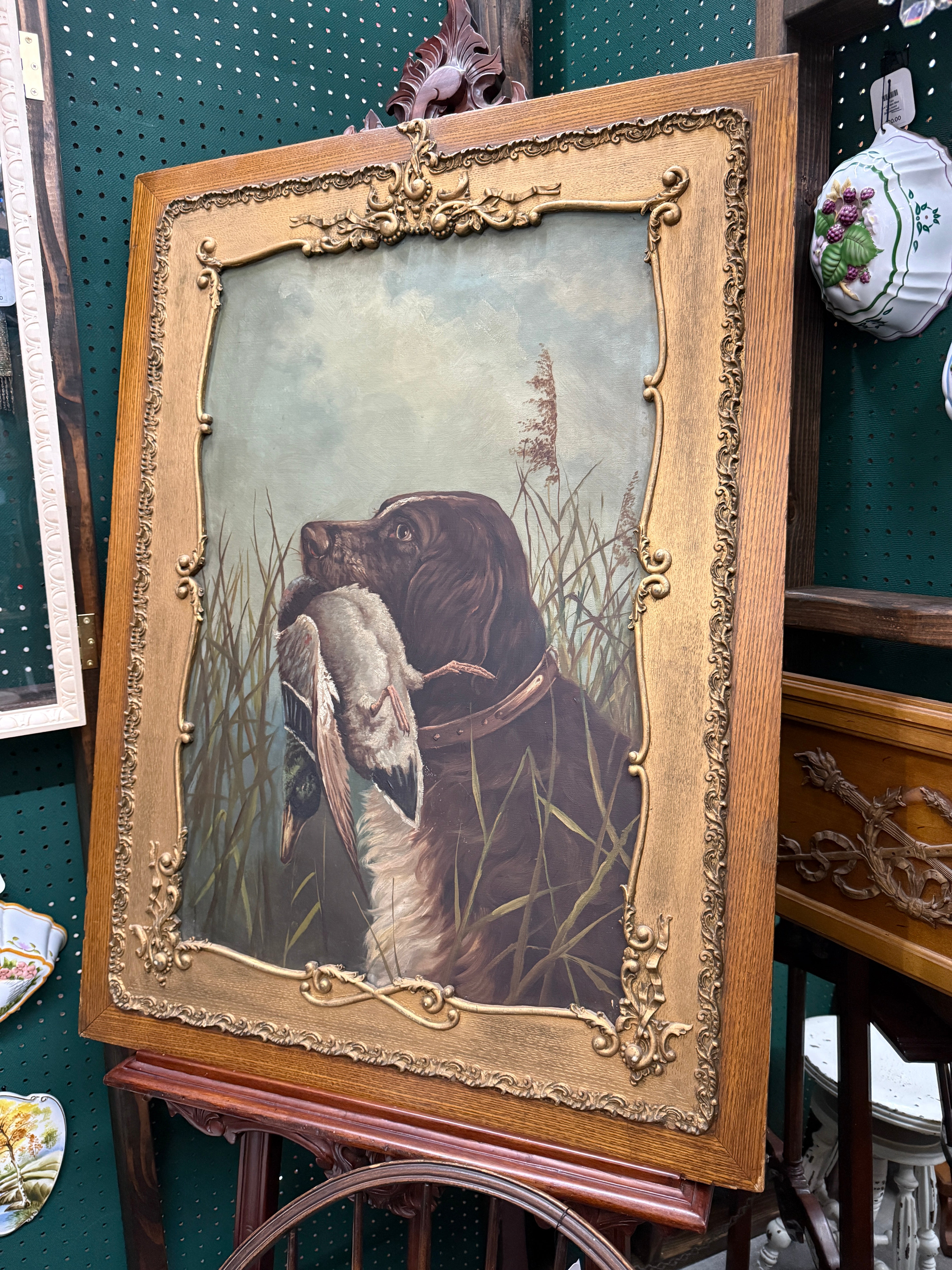 Framed artwork of a dog with a duck in a decorative setting