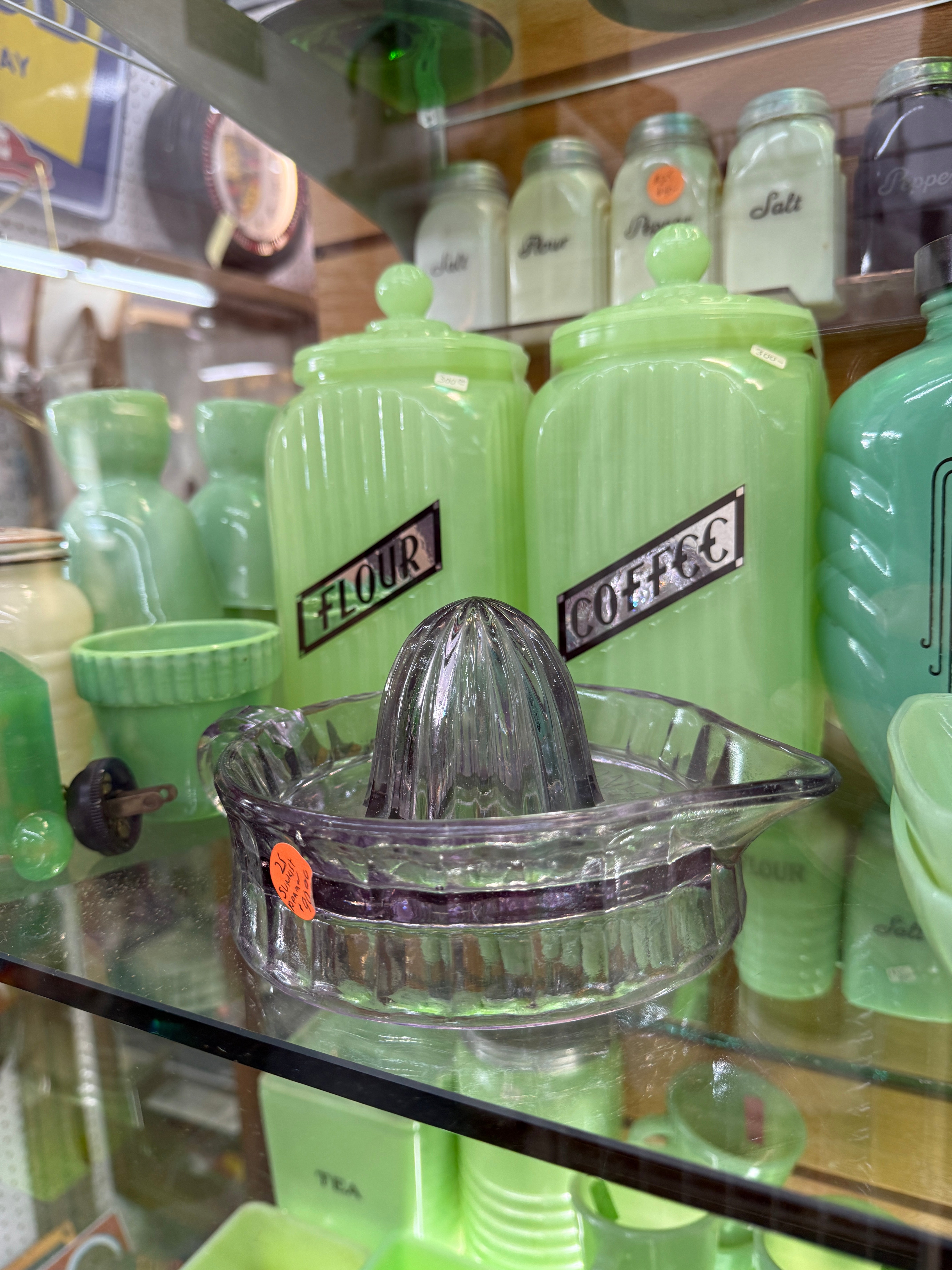Green manual juicers with clear plastic parts on a store shelf.