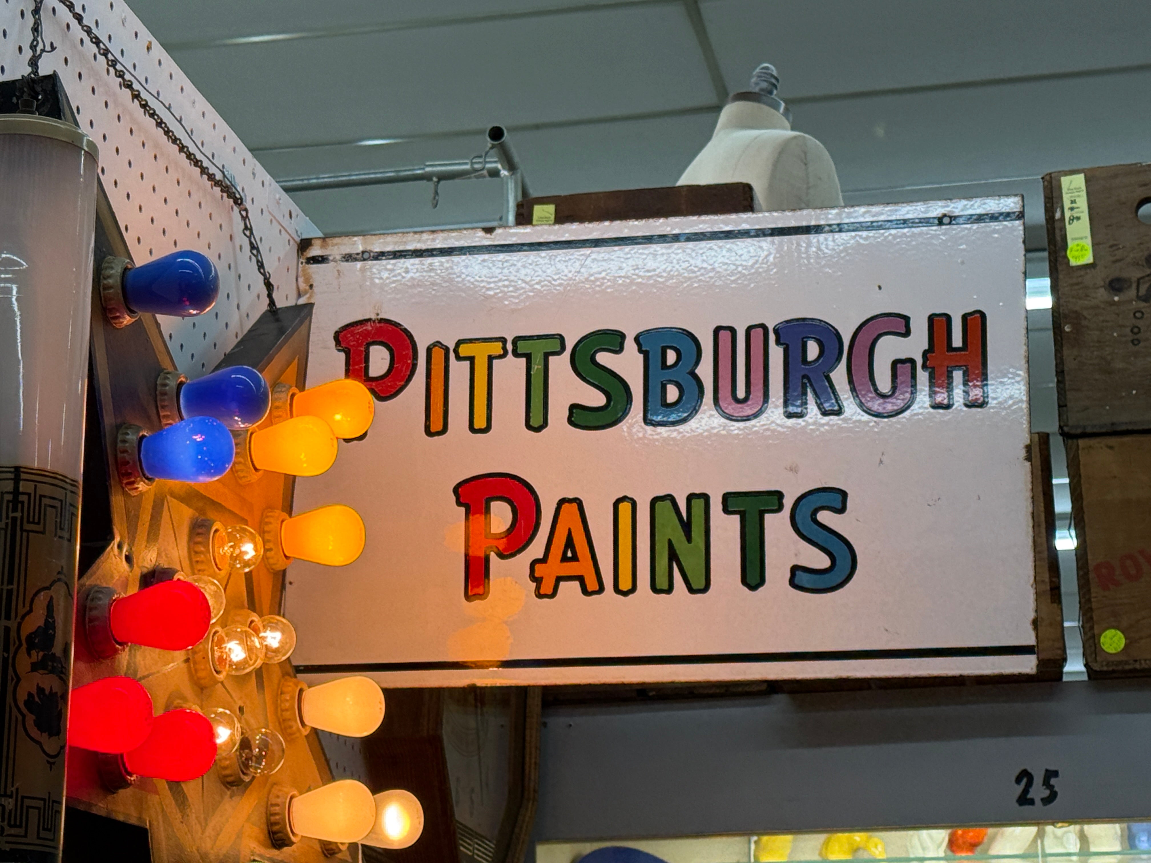Vintage-style sign with 'Pittsburgh Paints' text and colorful lights on a white background.